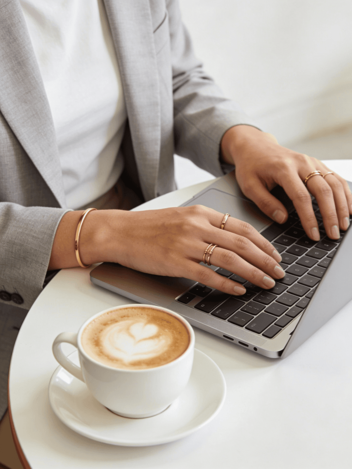A person typing on a laptop beside a coffee